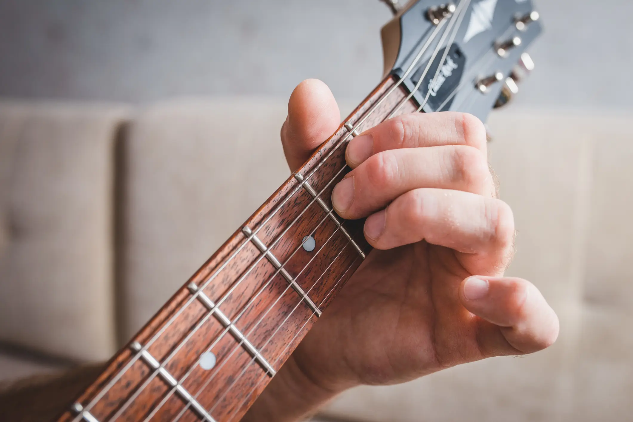 A hand fretting an open E minor chord on an acoustic guitar