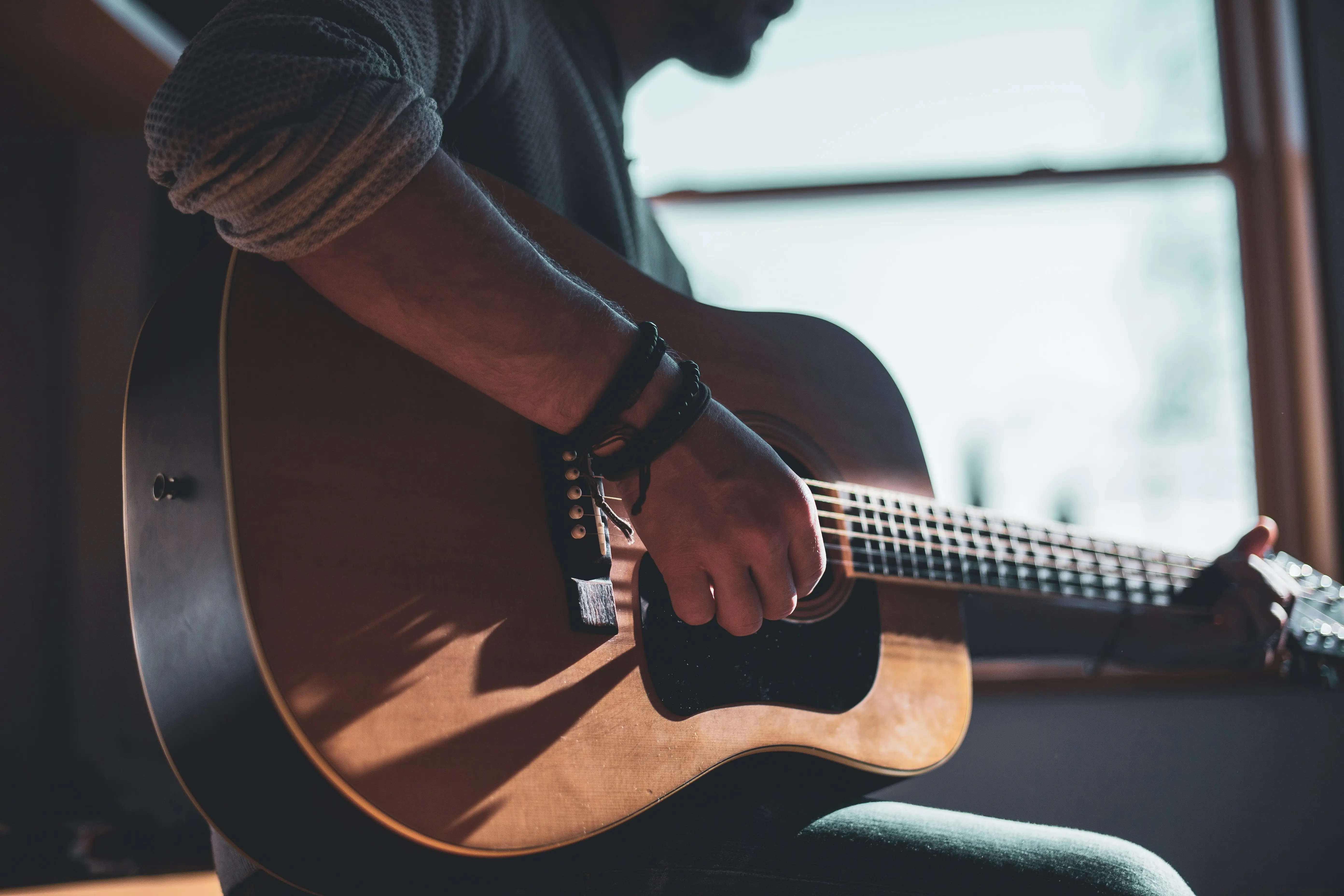 Person learning to play acoustic guitar at home